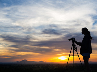 Silhouette of woman shooting with camera at sunset