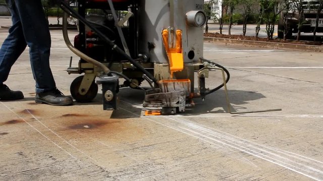 Man painting the yellow line on the concrete floor at car park