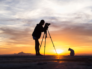 Silhouette of woman shooting with camera at sunset