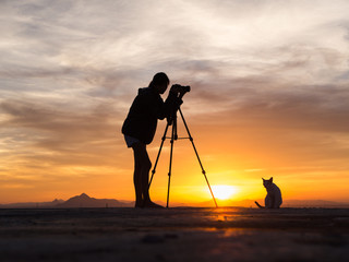 Silhouette of woman shooting with camera at sunset