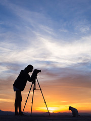 Silhouette of woman shooting with camera at sunset