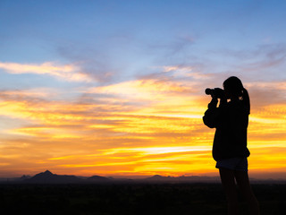 Fototapeta premium Girl photographer with camera at sunset