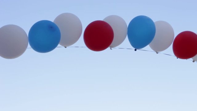 White, blue and red balloons trembling in the blue sky