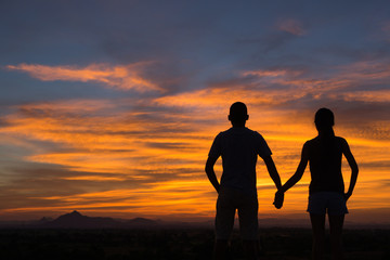 Fototapeta na wymiar Silhouette of Happy Young Couple Hugging Outside at Sunset