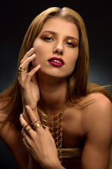 Obraz premium Fashion photo of attractive young blonde woman with styled make–up, long necklace and many rings on her fingers