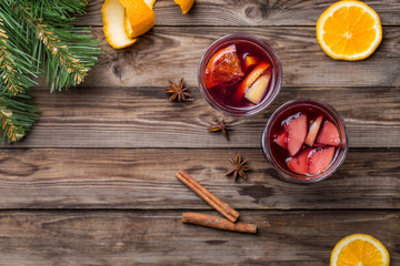 Two glasses of hot mulled wine with oranges, apples and spices