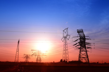 High voltage towers under the setting sun