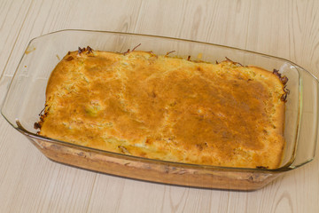 Pie with cabbage in glass brazier on wood table.