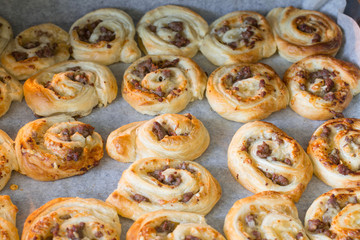 Puff pastry pizza rolls with minced beef on baking tray in oven.