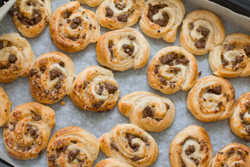 Puff pastry pizza rolls with minced beef on baking tray in oven.