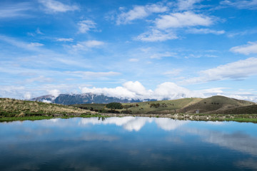Fototapeta na wymiar Cielo azzurro riflesso in lago di montagna