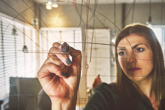 Creative Beautiful Businesswoman Writing On Glass Board In Offic