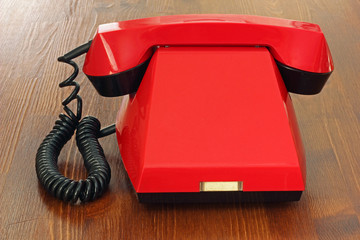 Red retro telephone on the wooden surface