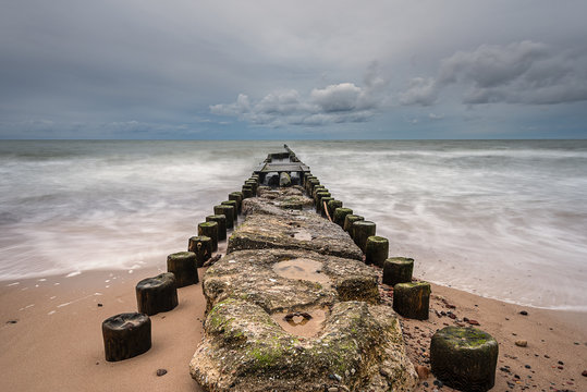 Old wooden breakwater on pebble beach in Wicie,  a small and charming village between Darlowo and Jarosławiec. Stormy day on Baltic Sea. Poland. Europe.