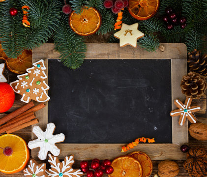 christmas gingerbread cookies with fir tree twigs frame with empty black chalkboard