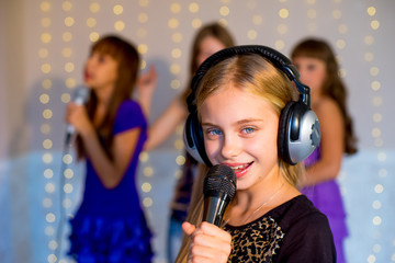 Group of happy girls singing on karaoke