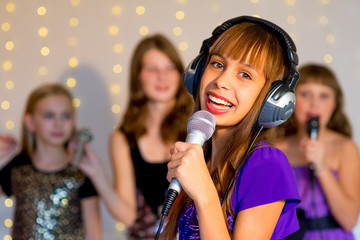 Group of happy girls singing on karaoke