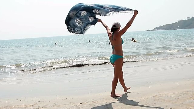 Happy young woman walking on the beach