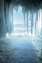 Lake Baikal. Ice grotto with long icicles in the coastal cliffs