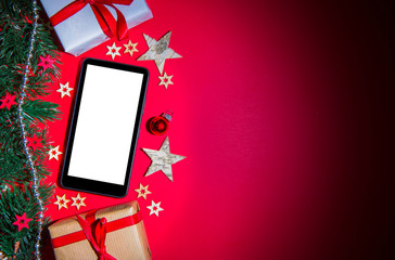Smartphone in Christmas red background with tree, gift and decor