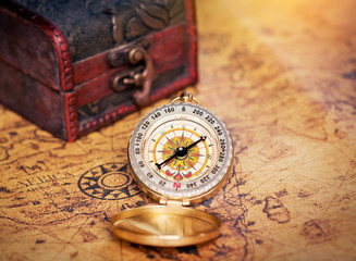 Old vintage compass with treasure Chest on map.