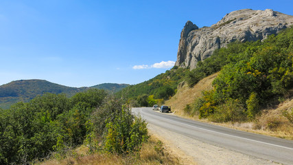 Rock in forest and road on blue sky background