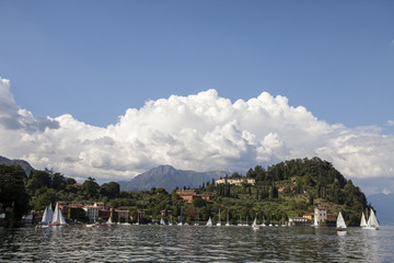 Fototapeta na wymiar punta Serbelloni a Bellagio sul lago di Como con nuvole, riflessi nell'acqua e barche a vela