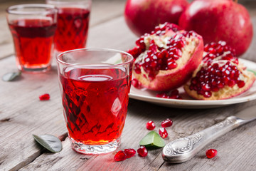 Whole and broken red ripe juicy pomegranates on rustic wooden unpainted table
