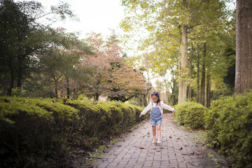 Fototapeta na wymiar 公園の歩道を歩く女の子