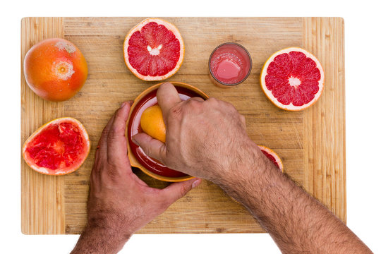 Man Squeezing Ruby Grapefruit Halves