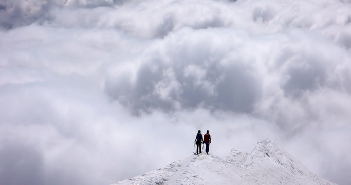 a mountain guide and client on an exposed rise in the Swiss Alps headed into an oncoming storm