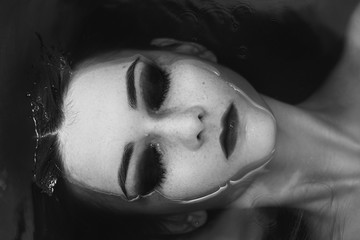 young beautiful woman lying in water, monochrome