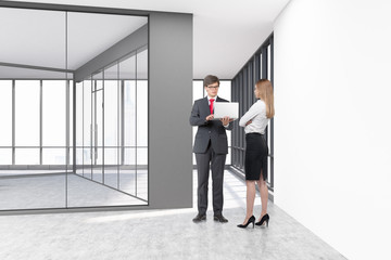 People in an empty office with glass and white concrete walls