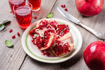 Whole and broken red ripe juicy pomegranates on rustic wooden unpainted table