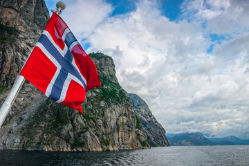 Fototapeta premium Norwegian flag against fjord mountains.