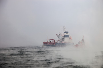 Dark image of ship and boats on sea during a violent blizzard.