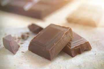 Some ounces of dark chocolate on white wooden table.