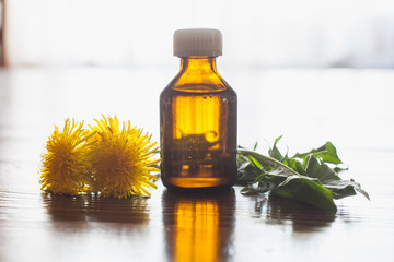 oil in a bottle and dandelions, selective focus