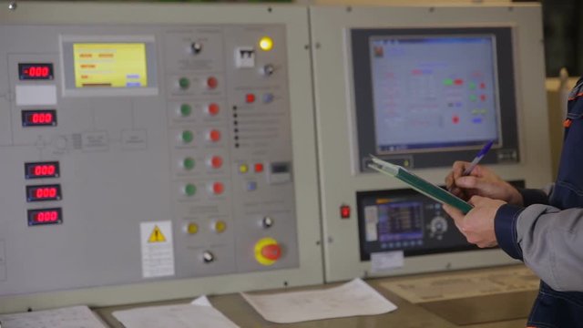 Industrial worker operating control paanel in control room of a industrial power factory. HD.