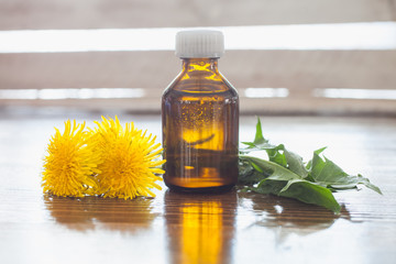 oil in a bottle and dandelions, selective focus