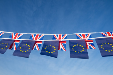 European Union and British Union Jack flag bunting flying in bright blue sky in a statement of the...