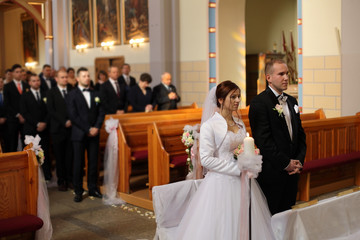 Młoda para w kościele w czasie ślubu. - obrazy, fototapety, plakaty