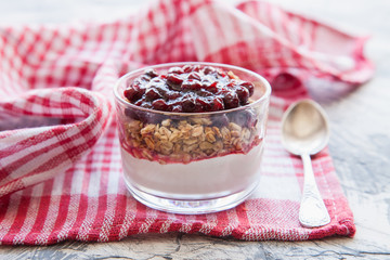 yogurt, muesli and cranberry jam in a glass on a table, selective focus
