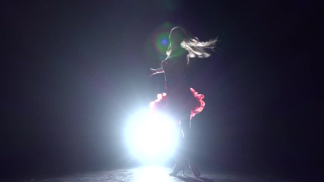 Girl dancing cha-cha-cha on a dark background with light illuminator. Slow motion