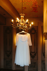 The bride's dress hanging on the chandelier