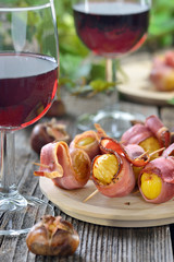 Gebackene Maroni im Südtiroler Speck als Fingerfood zum Törggelen mit regionalem Wein gereicht - Roasted chestnuts wrapped in South Tyrolean bacon served on skewers with local red wine