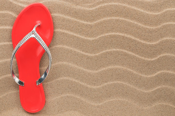 Pink flip flops with rhinestones on the wavy sand.