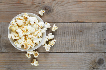 Popcorn in bowl on wooden table top view
