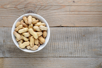 Roasted peanuts in bowl on wooden background