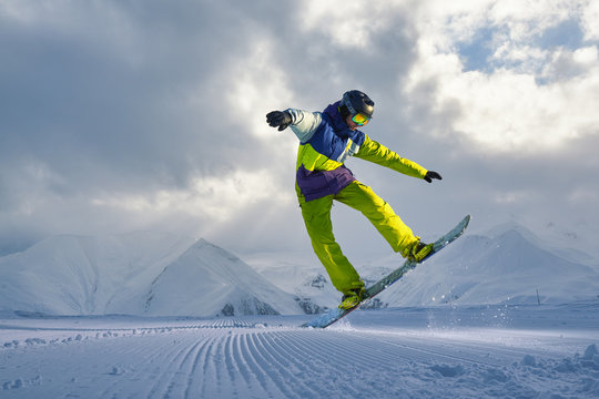 snowboarder does the jumping trick. snow scatters pieces